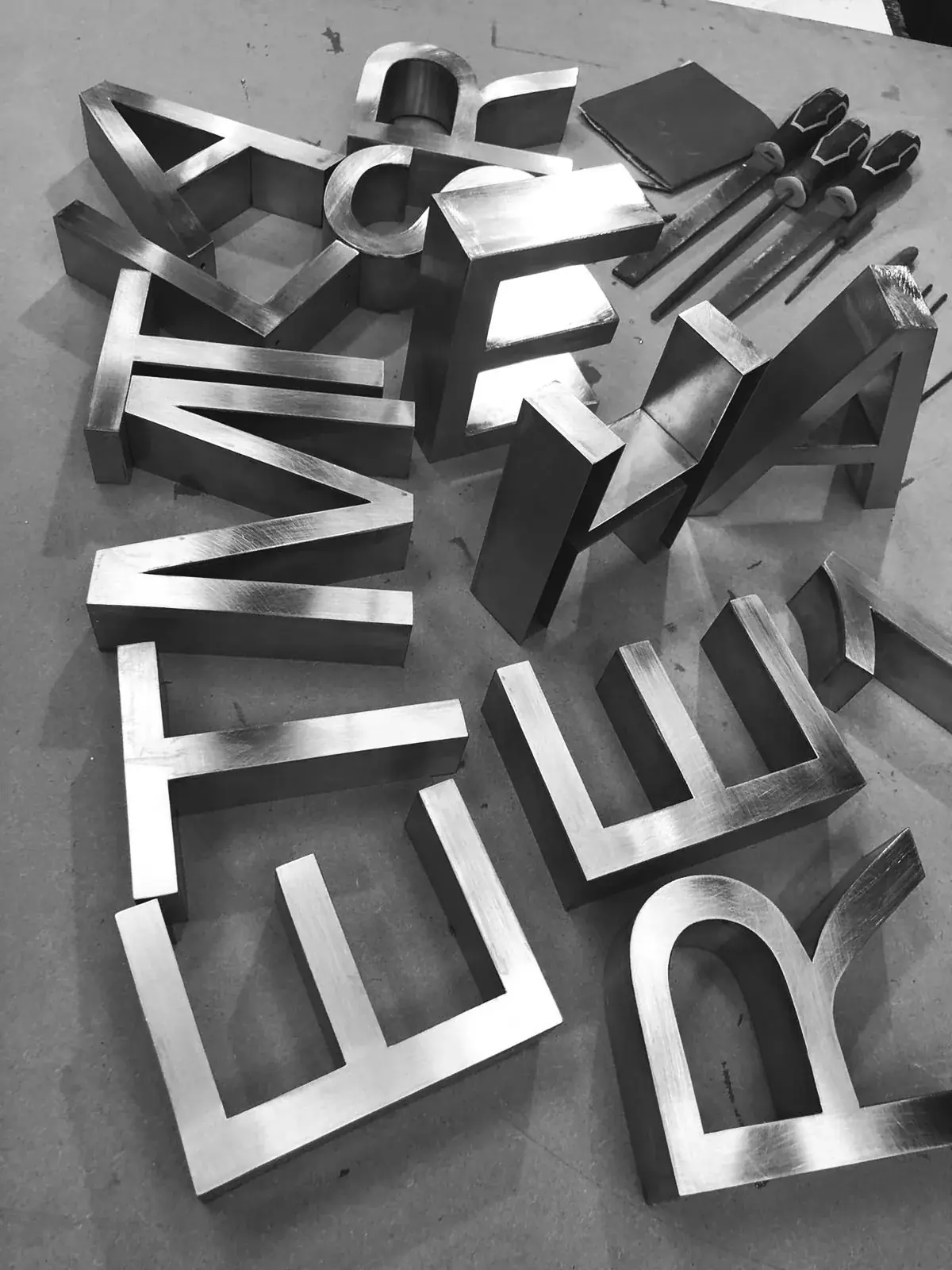 Fabricated metal relief letters and workshop tools viewed during production