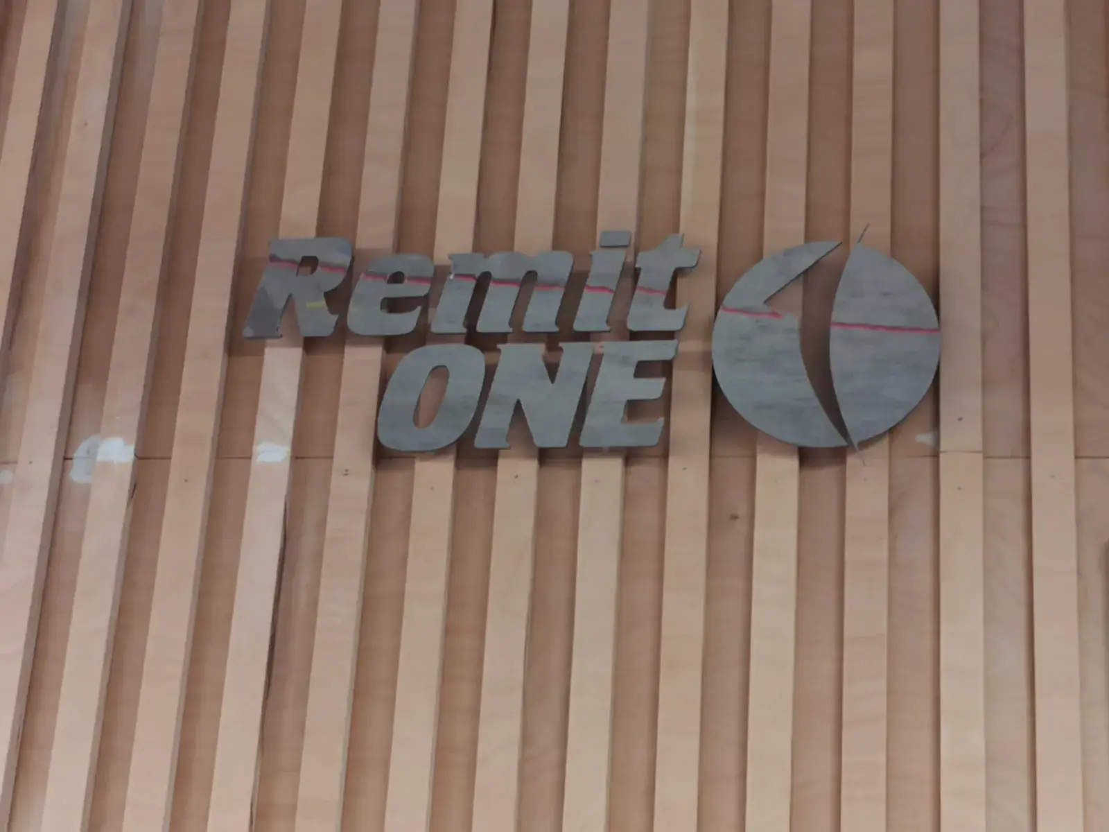 Remit One relief letters and dimensional logo installed on a timber feature wall — selected project for Central London