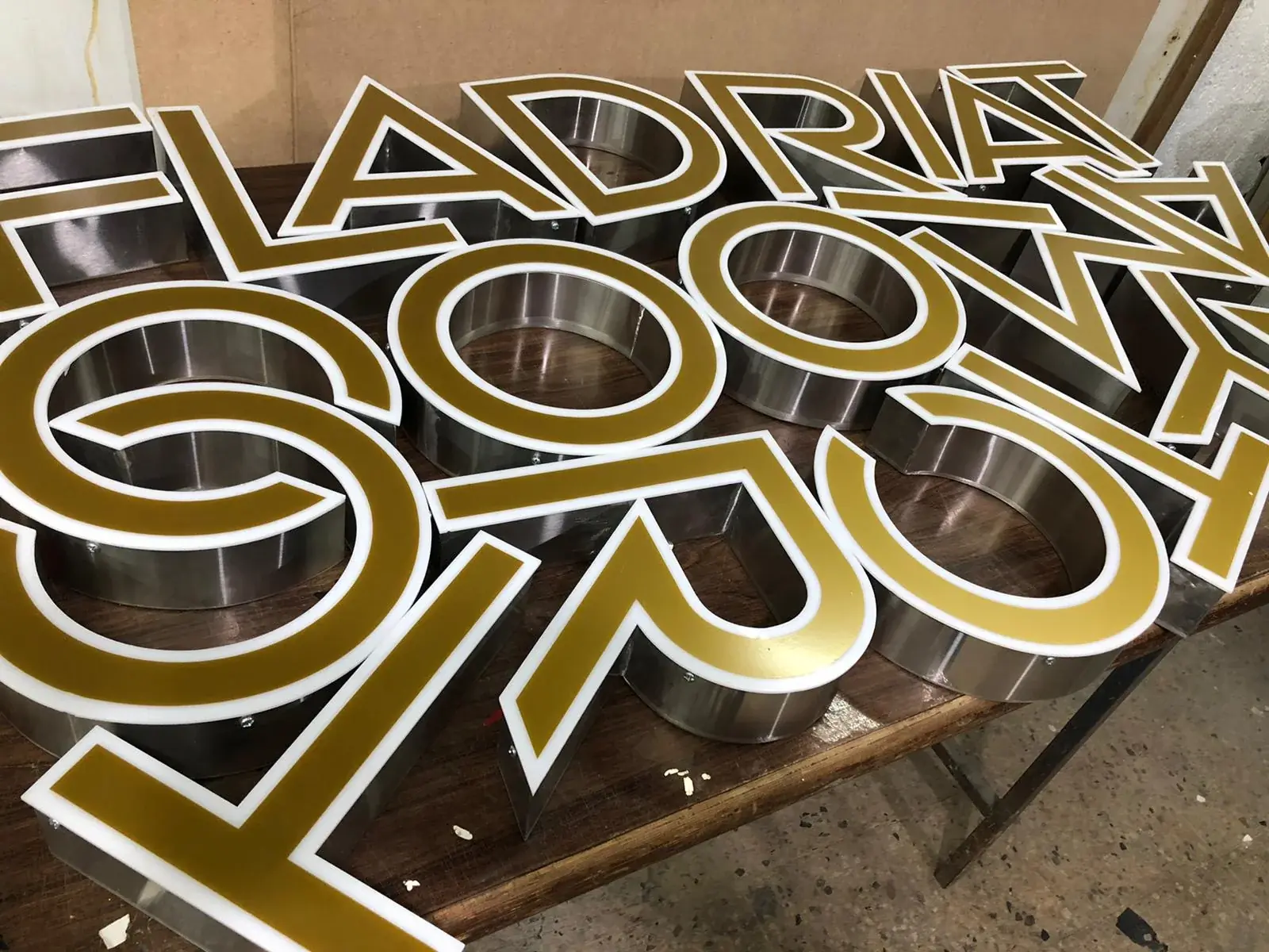 Gold-faced 3D built-up letters with stainless-steel returns arranged in the workshop — 3D Built-Up Letters example for Central London