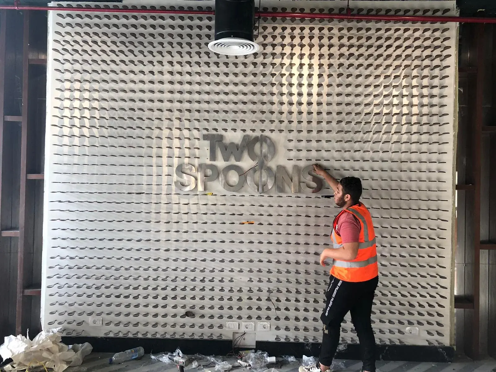 Two Spoons dimensional lettering being positioned on the spoon feature wall during installation