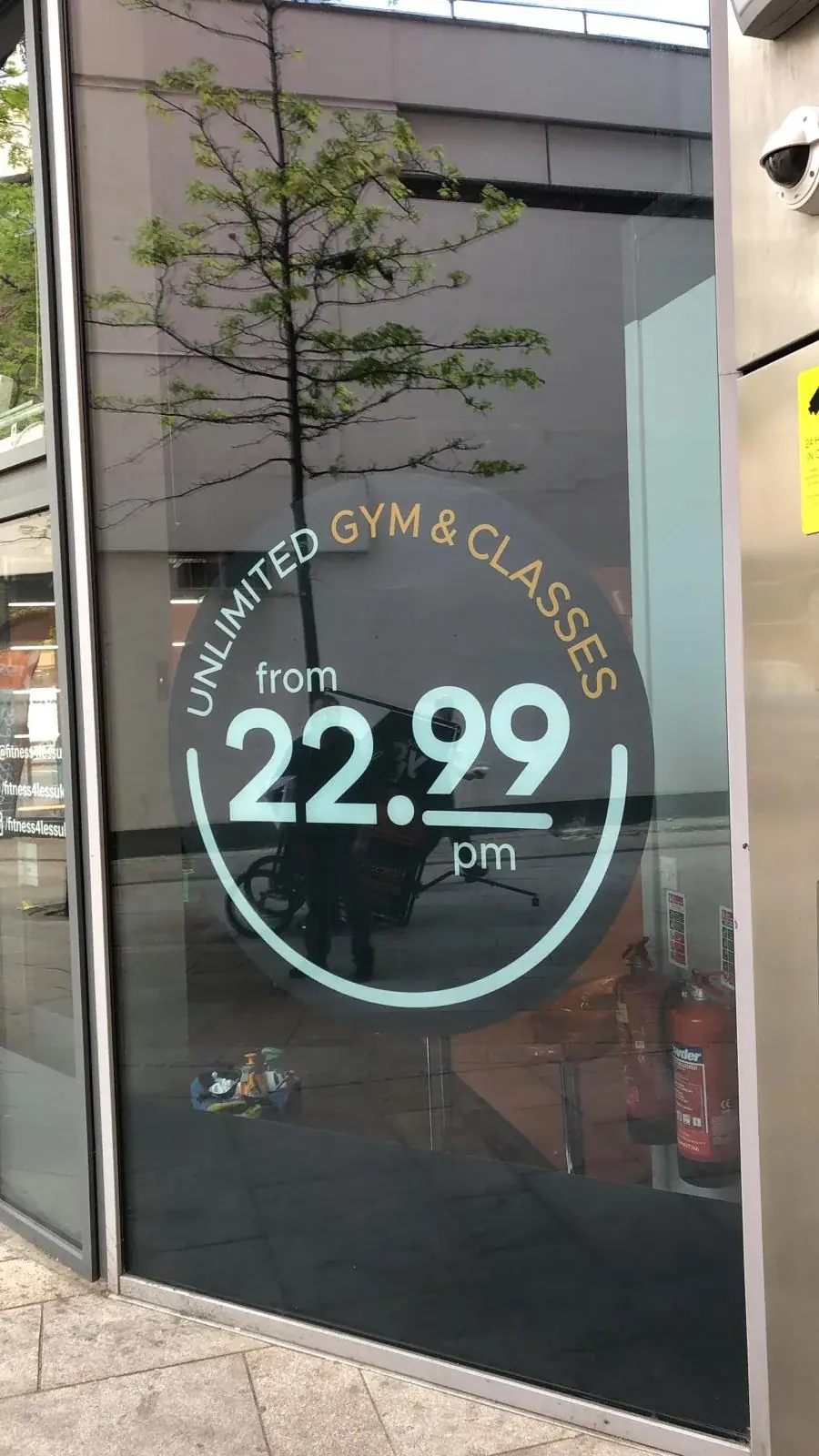 Fitness4Less membership price window graphics with street reflections