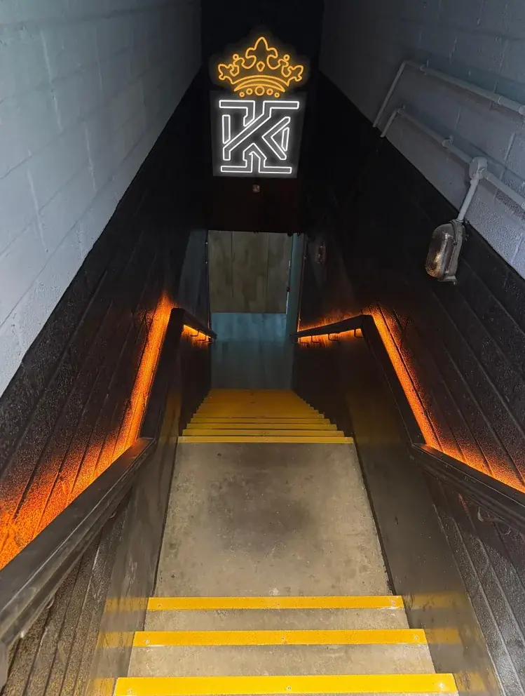 Completed Kings Gym Tower Bridge stairwell with illuminated crown and K logo, amber handrail lighting and yellow stair-edge details
