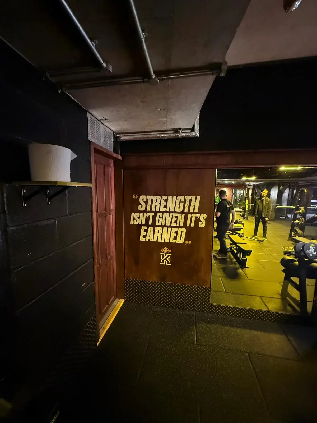 Strength is earned motivational wall graphic installed beside a gym mirror