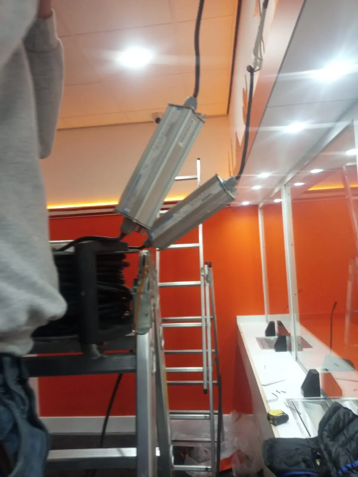 Lighting installation in progress above the Ria customer-service counter