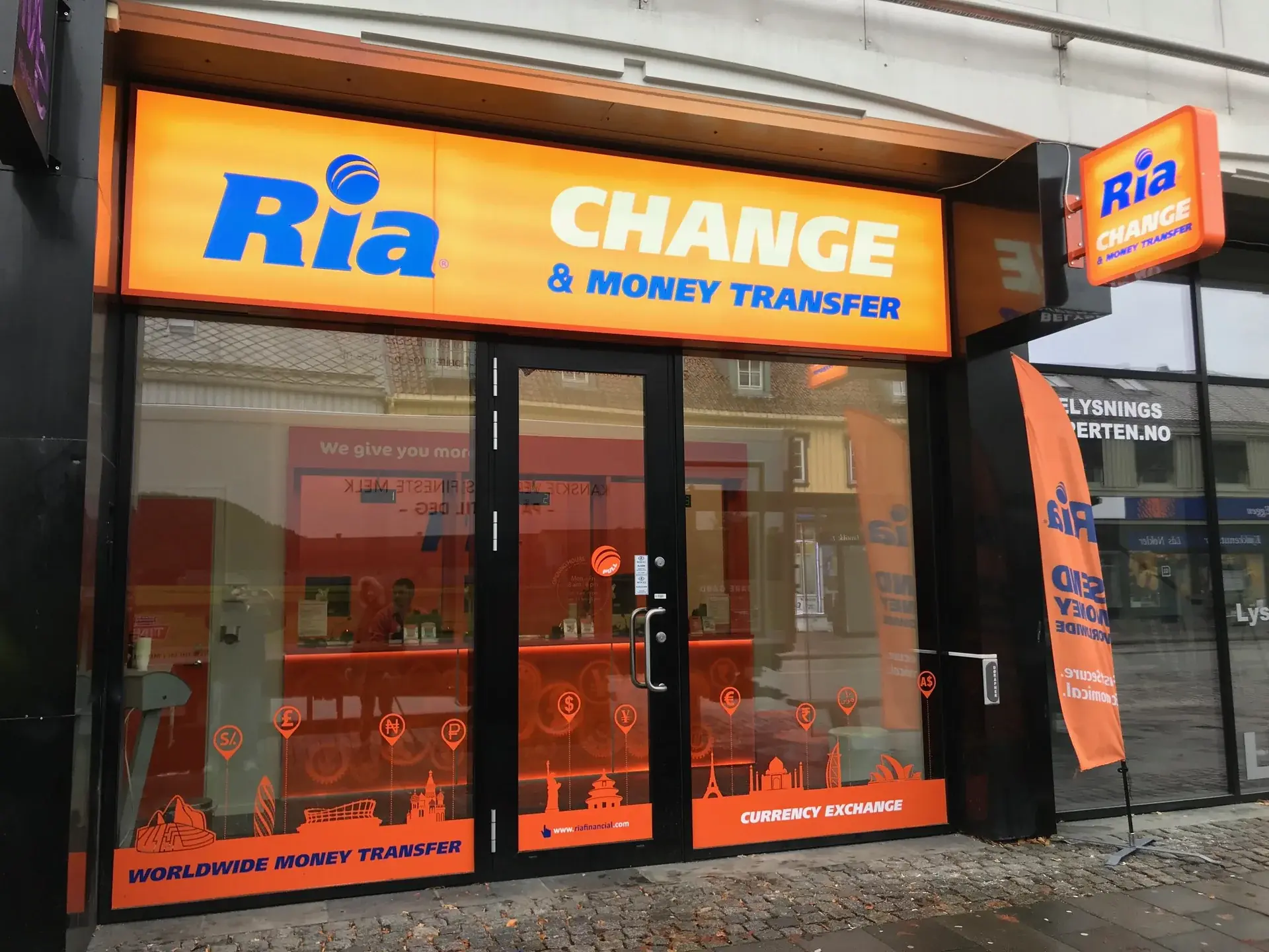 Angled view of the illuminated Ria fascia and projecting shopfront sign