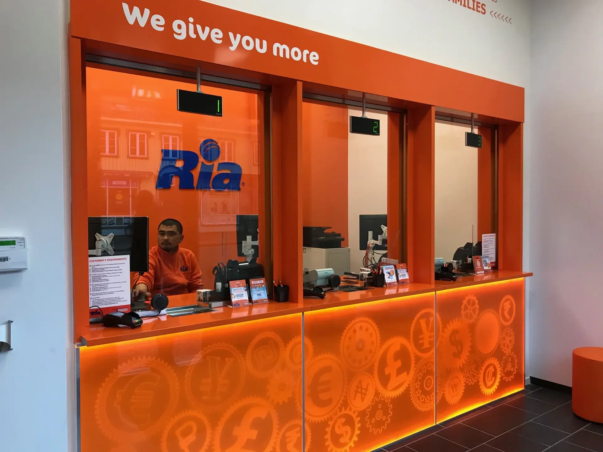 Ria Money Transfer interior counter with orange illuminated graphic panels and dimensional logo