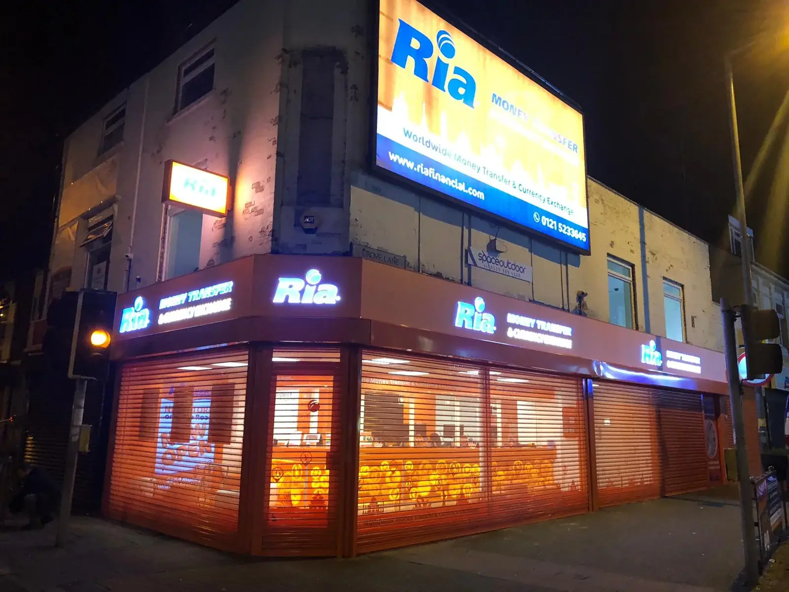 Ria Money Transfer illuminated exterior signage photographed after dark