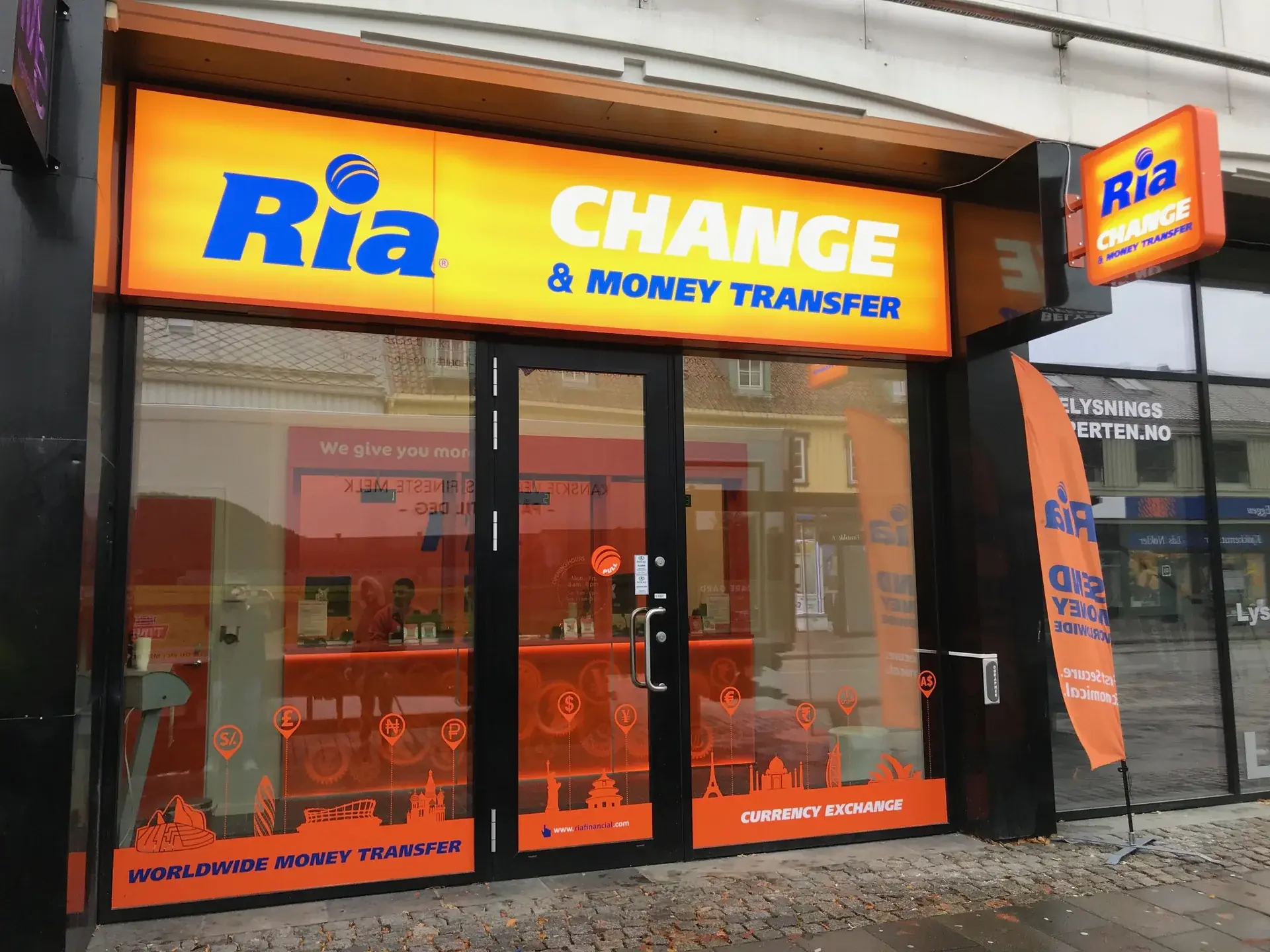 Ria retail branch exterior with coordinated window graphics and illuminated signs