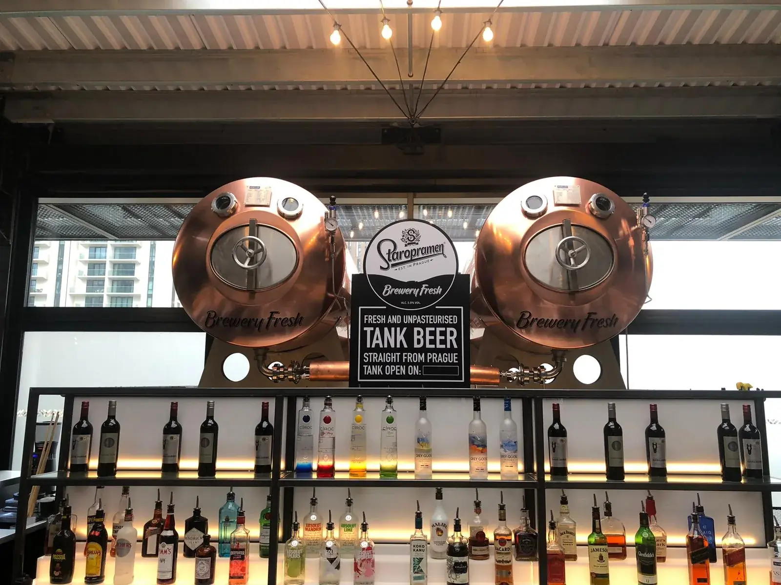 Twin Staropramen copper tanks with brewery-fresh vinyl branding behind a bar, gallery image 2