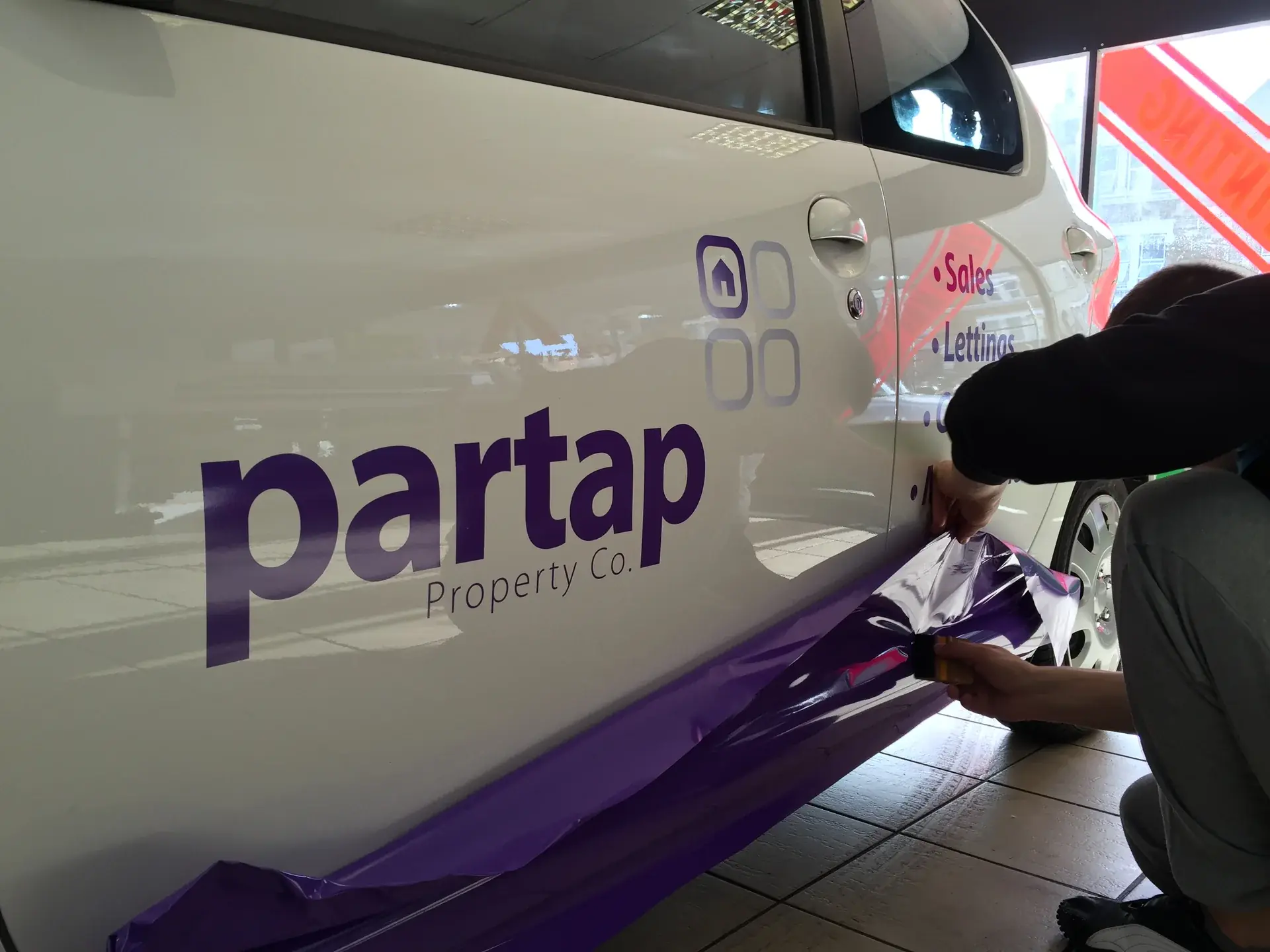 A sign fitter placing a graphic on a van side
