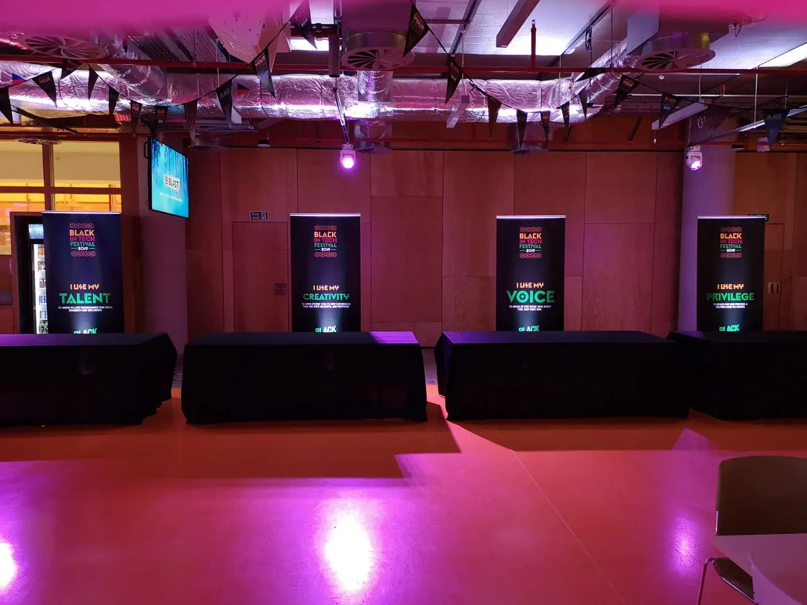 Four coordinated Black in Tech Festival roll-up banners behind registration tables